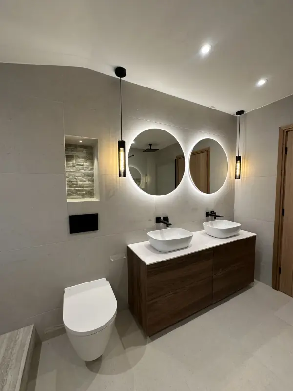 Light stone-effect wall and floor tiles behind a double vanity, with a split-face tile niche