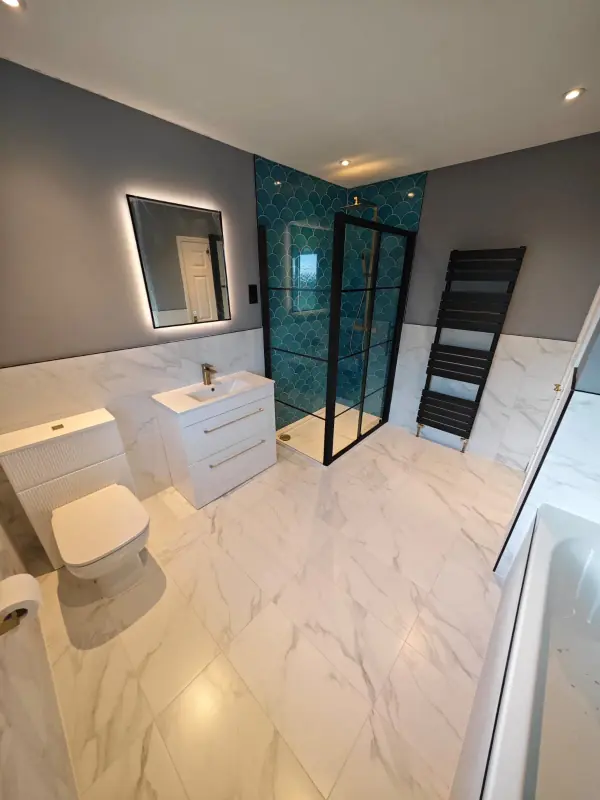 Bathroom with teal fish-scale tiles in the shower, white marble-effect floor tiles and half-height wall tiles