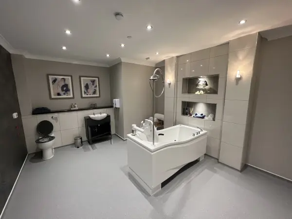 Large accessible bathroom with gloss wall tiles and two lit tiled niches