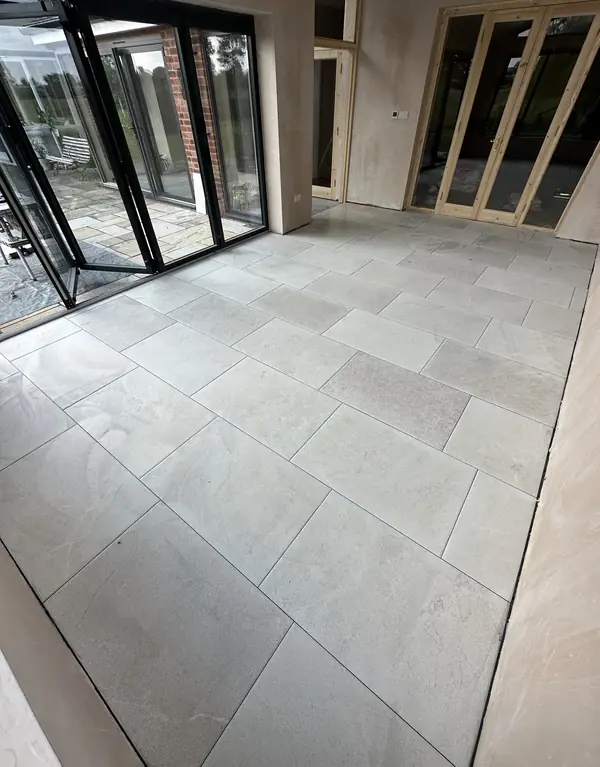 Large light grey stone-effect floor tiles laid across a garden room