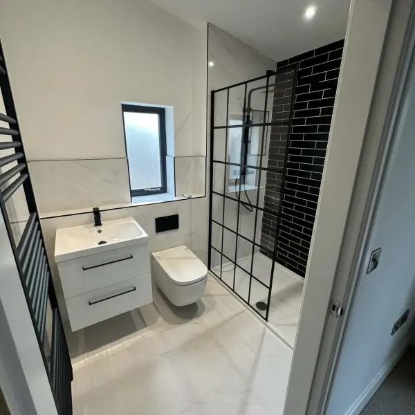 Black metro tiles in a walk-in shower, with white marble-effect tiles on the walls and floor